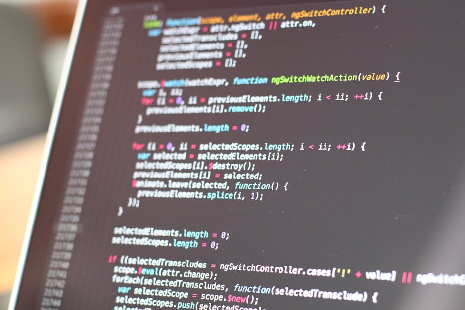 A close-up view of a laptop screen displaying lines of colorful programming code, with various syntax highlighting in shades of green, pink, blue, and white. The code appears to be JavaScript, featuri
